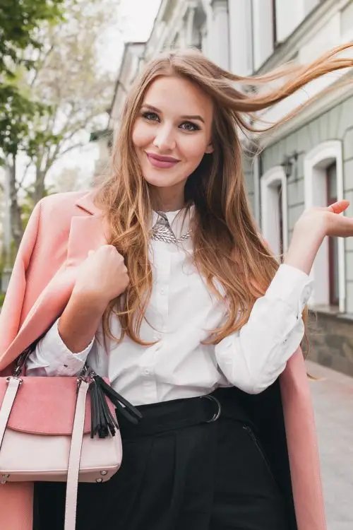 Stylish young woman smiling while walking in the city.